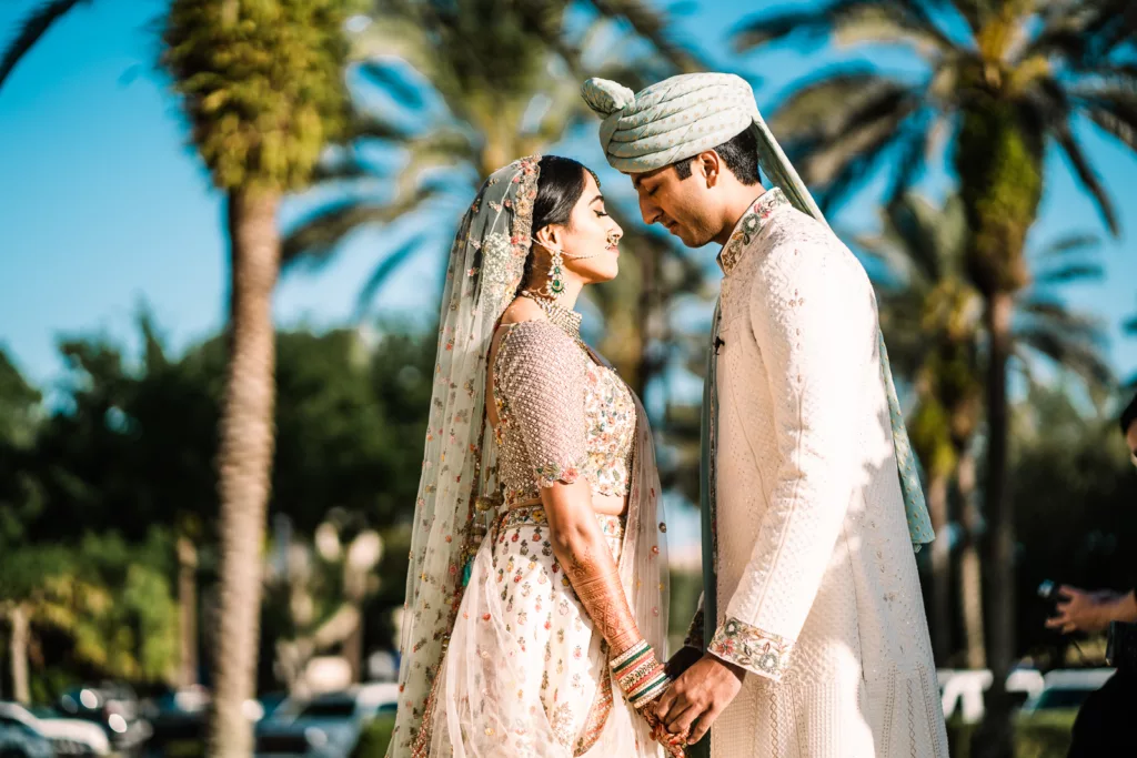 Indian Bride and Groom holding hands in front of palm trees at Gaylord Palms wedding.
