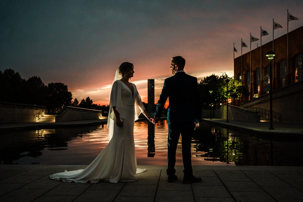 Bride and groom holding hands at sunset along a local canal.