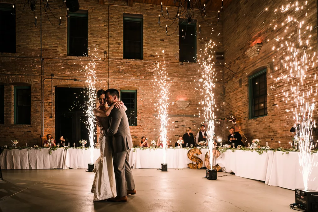 A bride and groom dance at thier wedding while cold sparks fly in the air.