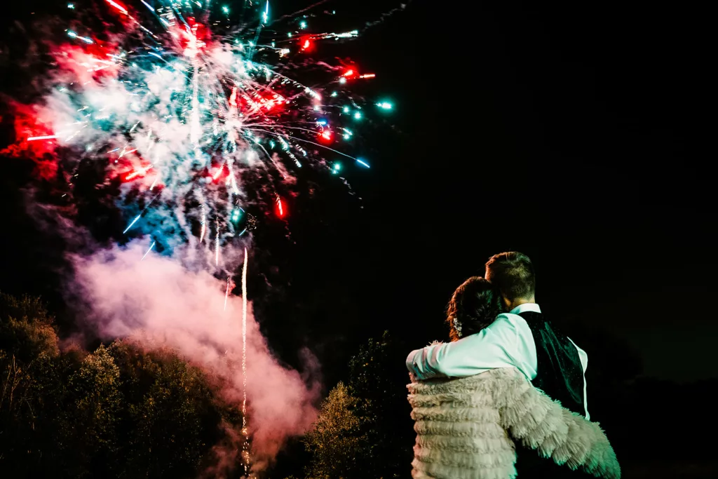 a couple watches fireworks at their wedding reception